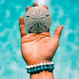 Beaded Turtle Bracelet on hand over turquoise ocean water