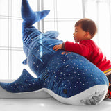Child playing with big whale shark stuffed animal