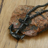 Front view of a black anchor necklace on rock display