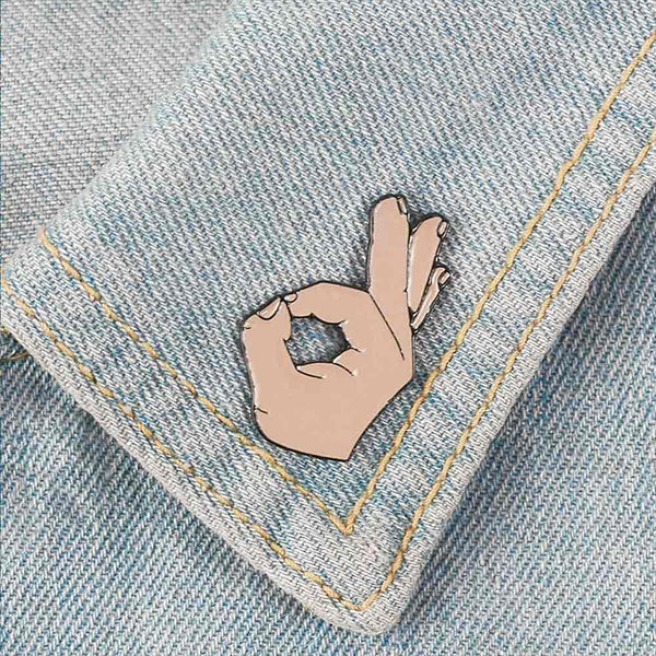 ‘OK’ gesture pin on denim collar