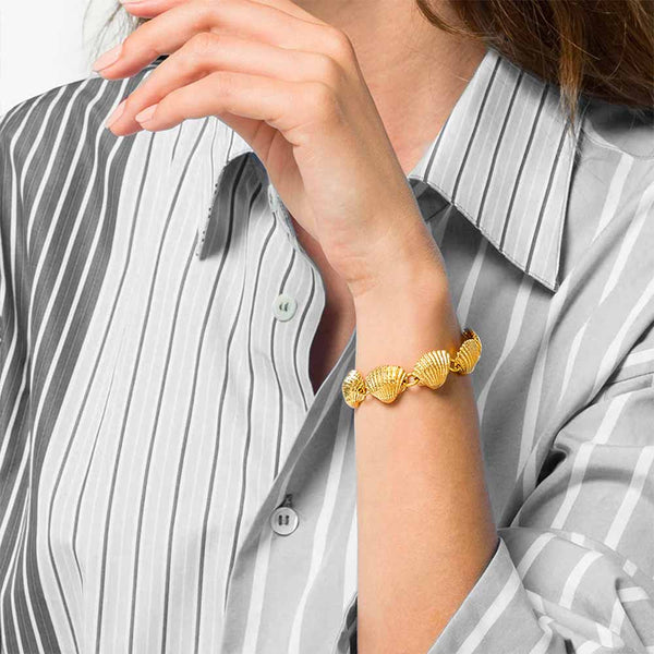 Woman in grey shirt wearing a bracelet with gold shells 
