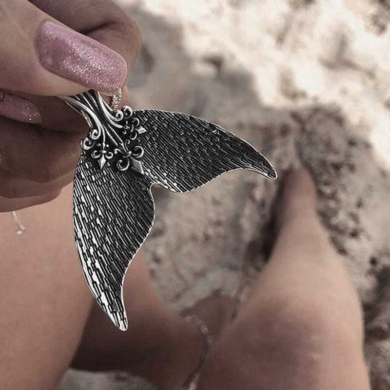 Woman at the beach holding a vintage style mermaid pendant